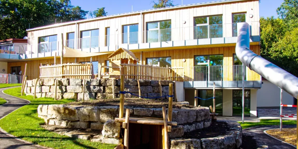 Kindergarten von Außen mit Rutsche und Spielplatz
