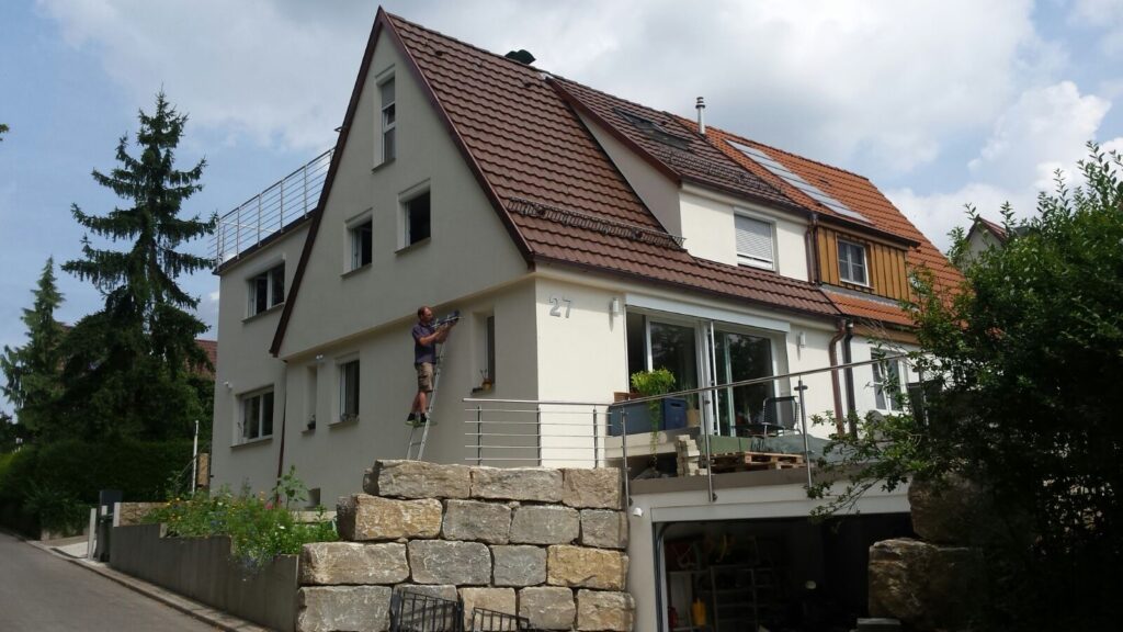 Familienhaus, davor ein Handwerker auf einer Leiter bei Arbeiten am Haus